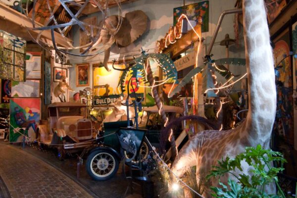 A stuffed giraffe model roped off next to miscellaneous safari memorabilia at ARTISANworks in Rochester, NY